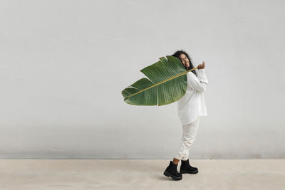 Woman holding umbrella against wall