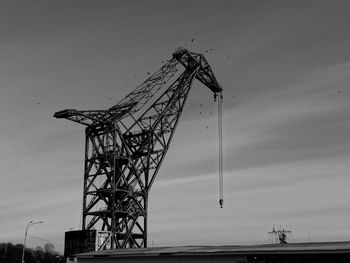 Low angle view of crane at construction site against sky