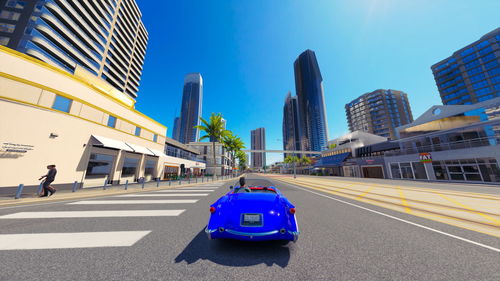 Traffic on road by buildings against blue sky