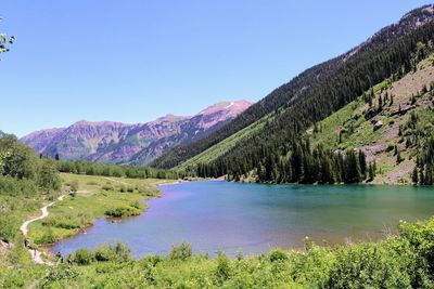 Scenic view of lake and mountains against clear blue sky