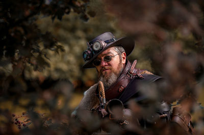 Portrait of man wearing hat aiming gun