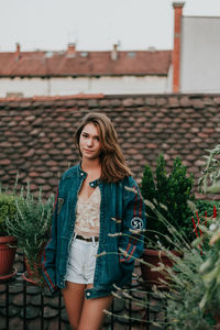 Portrait of smiling young woman standing against plants