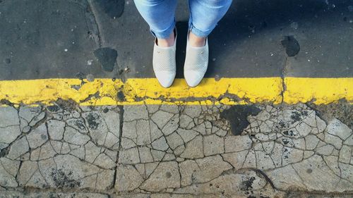 Low section of woman standing on cracked footpath