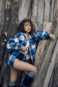 Portrait woman in a plaid shirt stands against the background of an old barn house in the village 