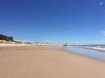 Scenic view of beach against clear blue sky