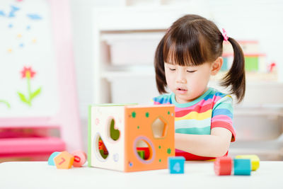 Cute girl playing with number block toy at home