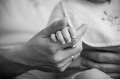 Close-up of father holding baby hand at home