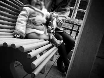 Low section of mother with daughter sitting on bench