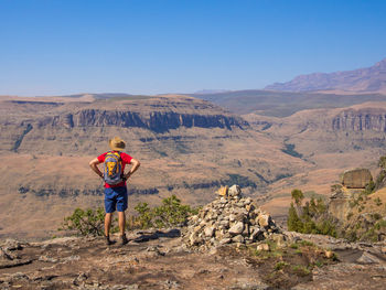 Rear view of man standing on desert against mountain