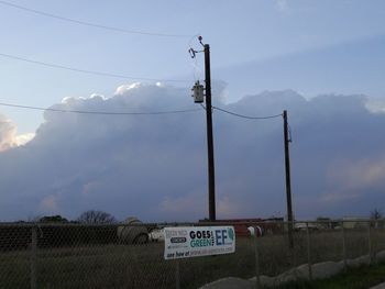 Road sign on field against sky