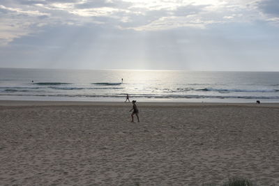 Man standing on beach against sky during sunset