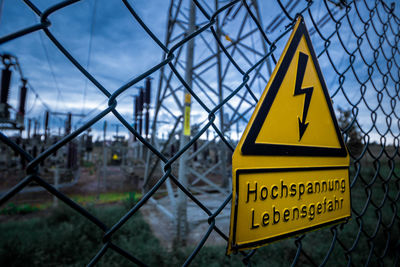 Close-up of yellow information sign against sky