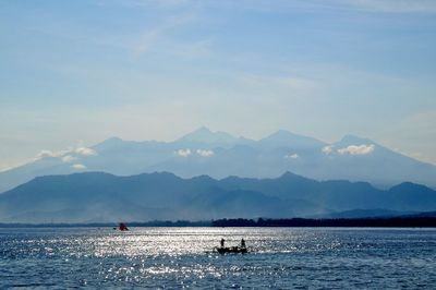 Scenic view of sea by mountains against sky