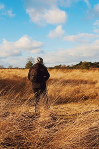 Man walking on field against sky