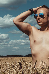 Man wearing sunglasses on field against sky