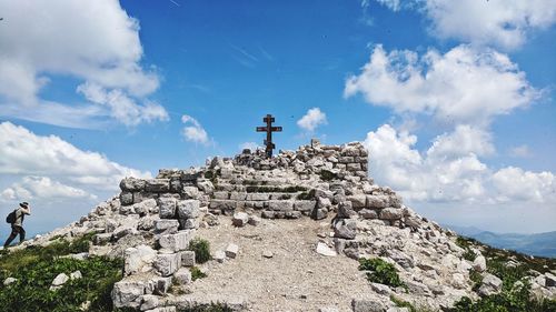 Low angle view of cross on rock against sky