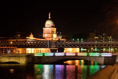 Illuminated buildings by river at night