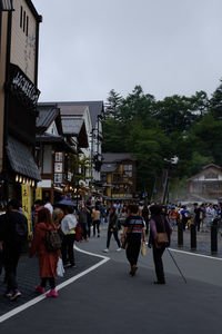 People walking on street in city against sky