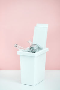 White bucket for sorting recyclables for glass on a pink background with emty space for text