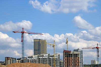 Cranes on construction site against buildings in city