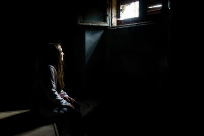 Side view of woman sitting at home