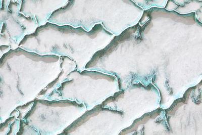 White-turquoise texture of pamukkale calcium travertine in turkey, uneven pattern of big cells