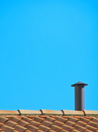 Smoke stack on roof against clear blue sky