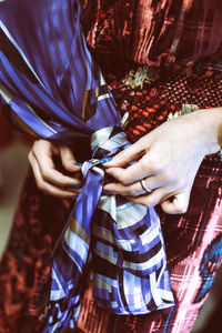 Woman's hand tying silk blue fabric on dress
