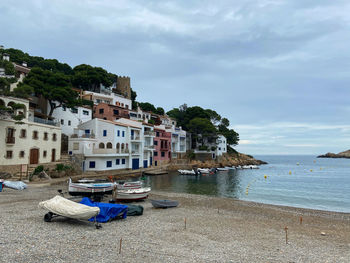 Boats moored on sea by buildings against sky