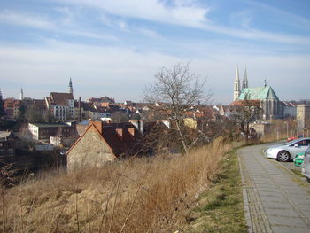 Cars on road by buildings against sky