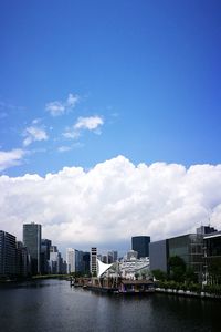 River by cityscape against blue sky