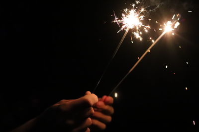 Cropped hands of person holding sparklers at night