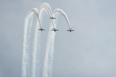 Low angle view of airplanes flying against sky during air show