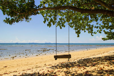 The view on a beach with sea, blue sky and white sand on a sunny day.