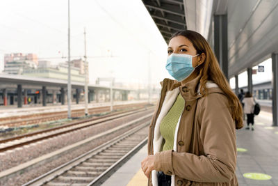 Beautiful woman in a medical mask waiting train on station