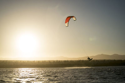 Young male athlete kiteboarding at sunset in la ventana, baja california, mexico