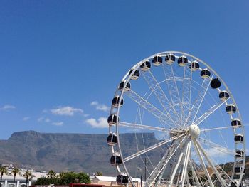 Low angle view of ferris wheel against blue sky