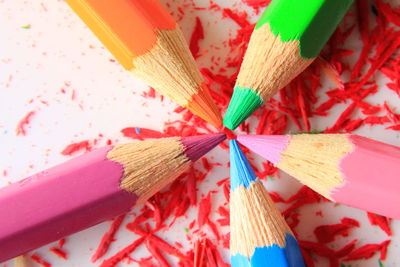 Close-up of colored pencils with shaving over white background