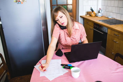 Woman using mobile phone while sitting on table