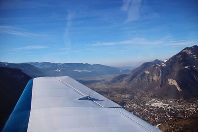 Airplane flying over mountains against blue sky