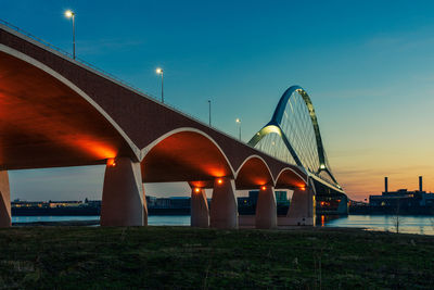 The de oversteek bridge in the dutch city of nijmegen is illuminated in the evening.