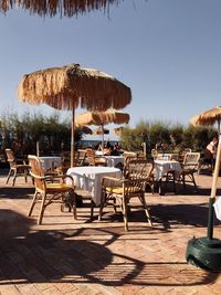 Chairs and table against sky on sunny day