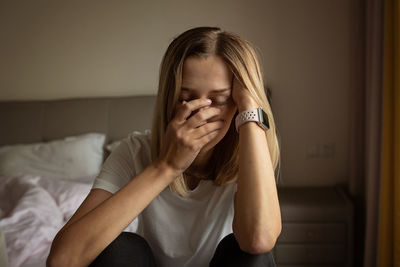 Portrait of young woman sitting on bed at home