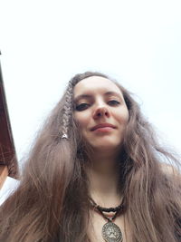 Low angle portrait of woman against sky