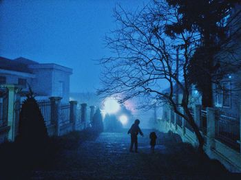 People walking on street amidst buildings against sky at night