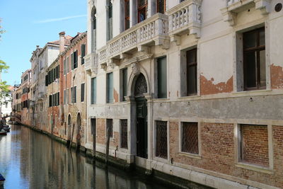 Buildings by canal against sky in city