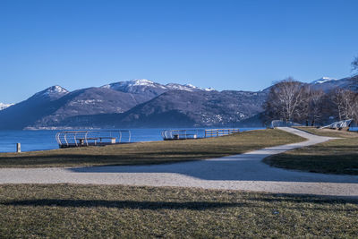 Scenic view of lake by mountains against clear blue sky