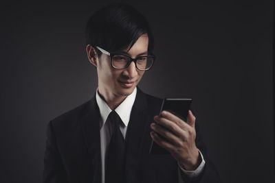 Young man using smart phone against black background