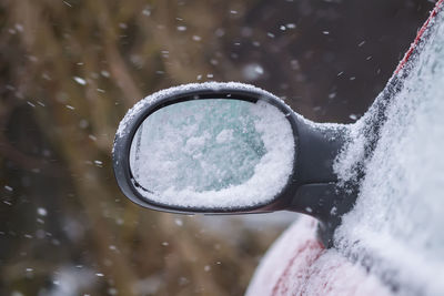 Car wing mirror covered up with fresh wet snow.