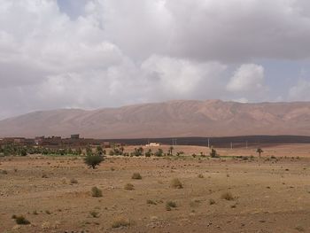 Scenic view of desert against cloudy sky